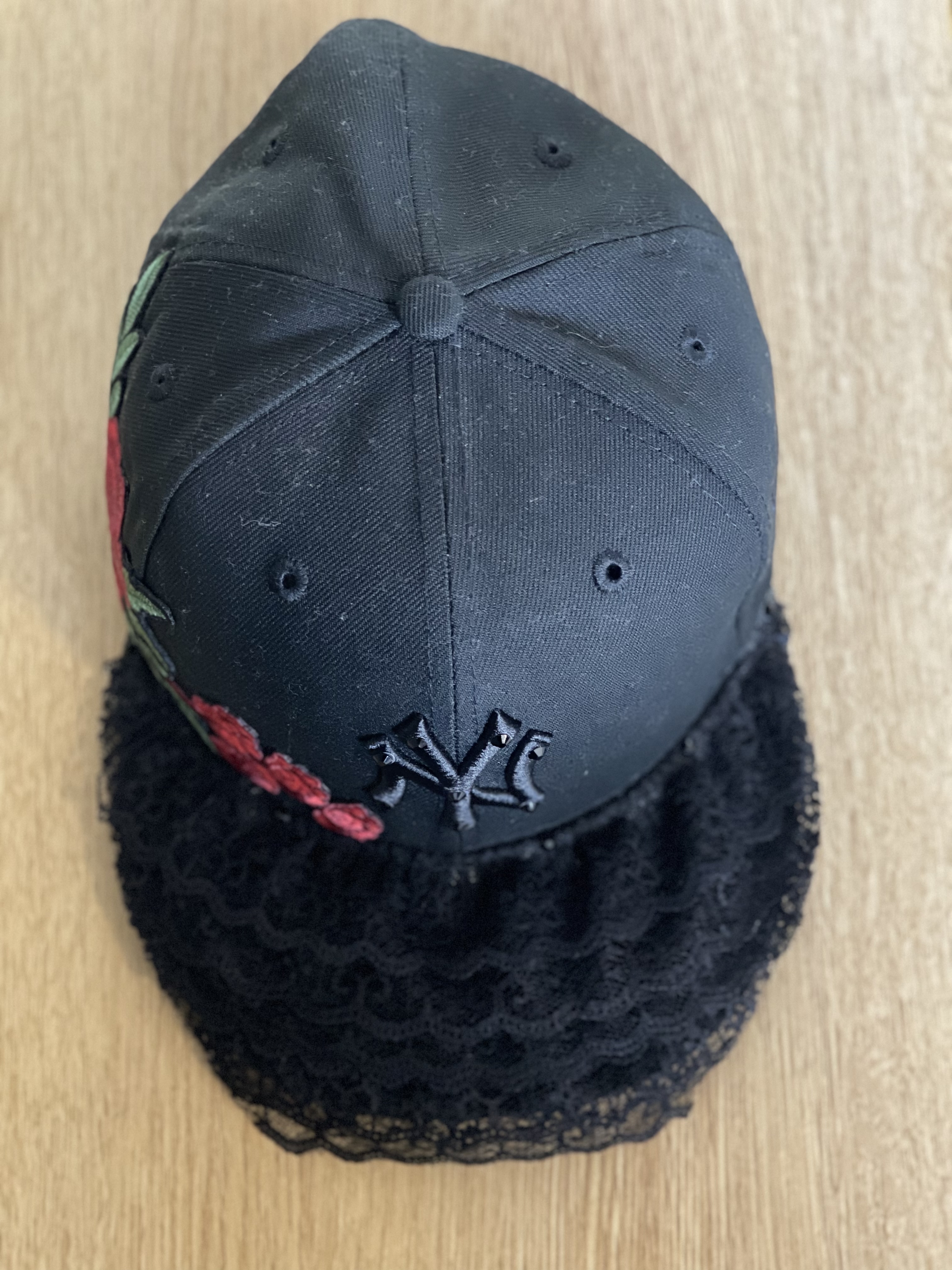 Black Yankees snapback with red floral embroidery and layered lace brim, top view.